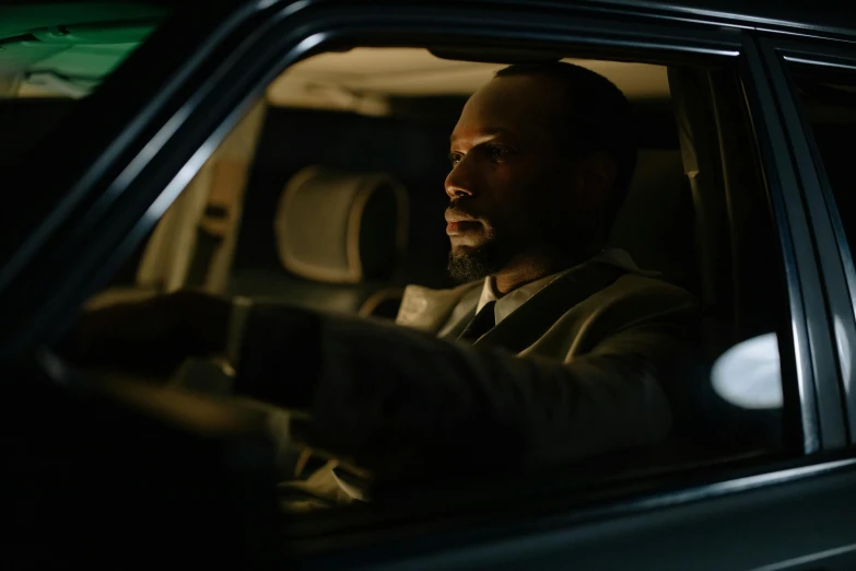 a man sitting in the passenger seat of a car, noire moody scene, 8 k movie still, light cinematic, george pemba