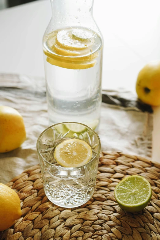 a pitcher of lemonade next to a glass of lemonade, a still life, trending on unsplash, renaissance, crystal clear water, glass bottle, with lemon skin texture, small glasses