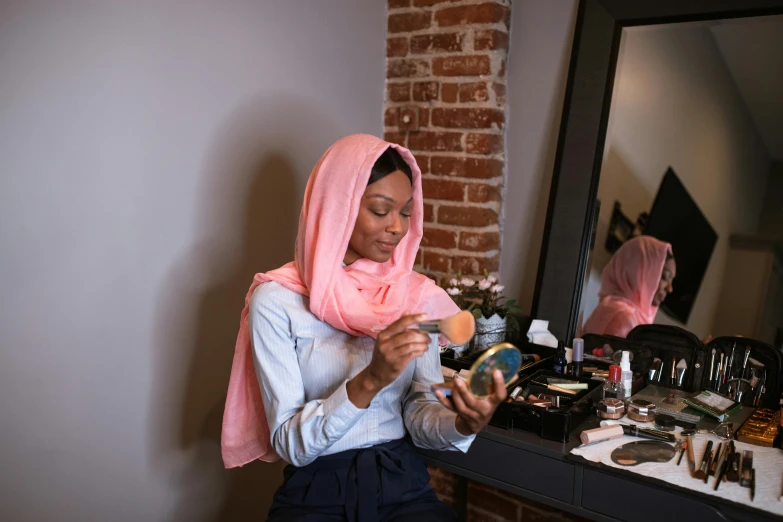 a woman putting on makeup in front of a mirror, hurufiyya, wearing a head scarf, profile image, photoshoot for skincare brand, casually dressed