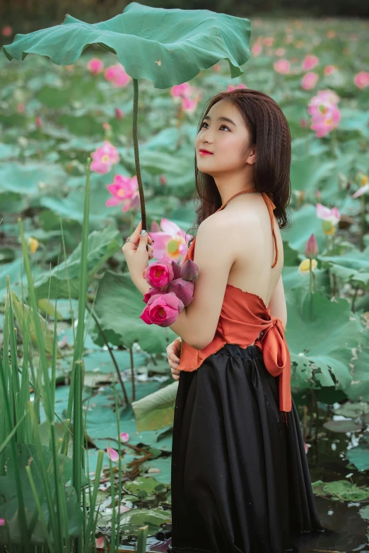 a woman standing in a pond holding an umbrella, inspired by Lan Ying, pexels contest winner, wearing black camisole outfit, with lotus flowers, bae suzy, lush surroundings