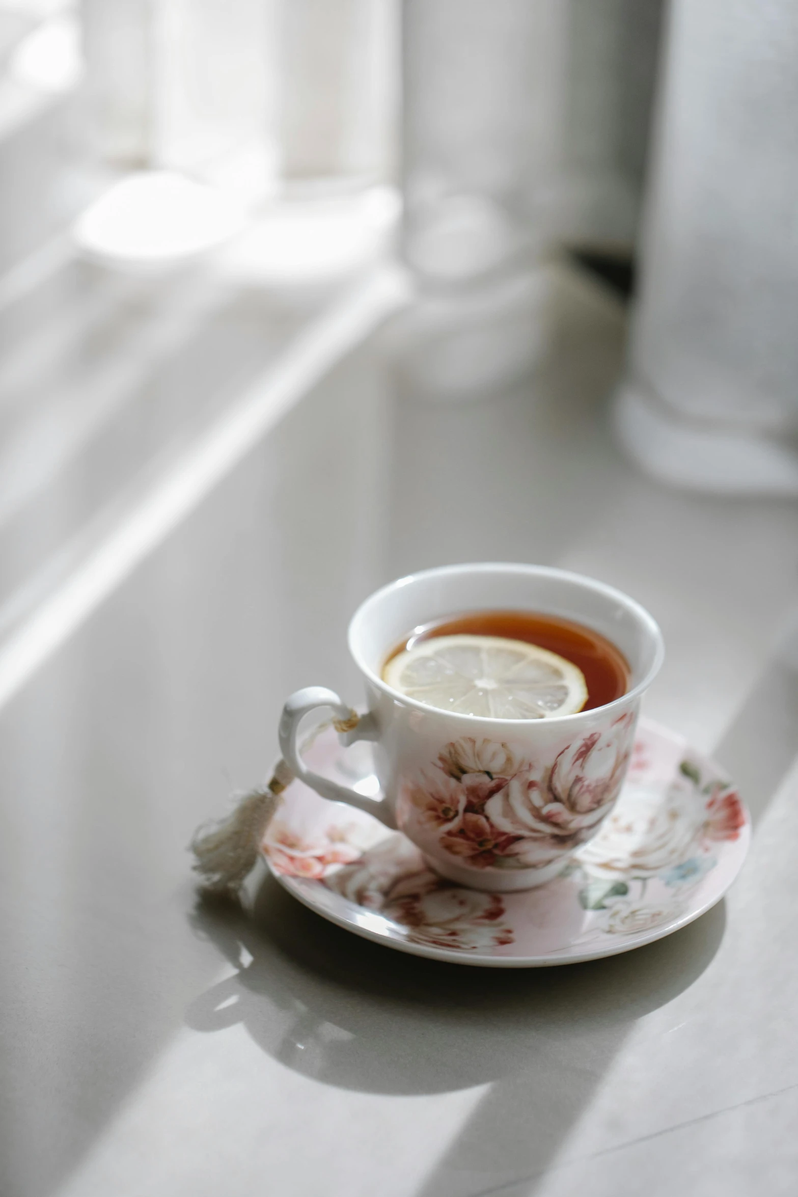 a cup of tea with a slice of lemon on a saucer, by Pamela Ascherson, unsplash, romanticism, square, soft window light, high quality photo, small