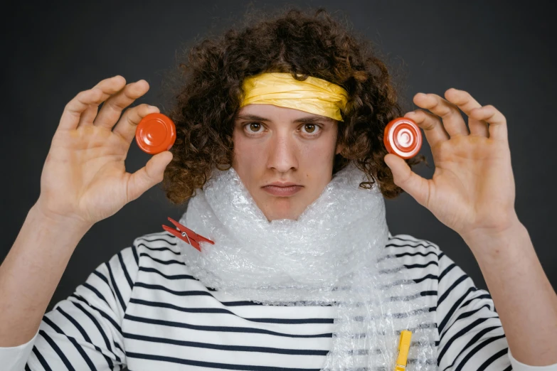 a man with curly hair holding a pair of scissors in front of his face, a portrait, inspired by Julius Klinger, pexels contest winner, plasticien, a woman holding an orb, white bandage tape on fists, plastic wrap, with a bunch of stuff