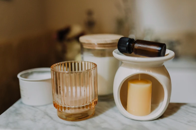 a candle sitting on top of a table next to a glass, a still life, inspired by Giorgio Morandi, trending on pexels, lots of jars and boxes of herbs, on a pale background, bath, porcelain organic