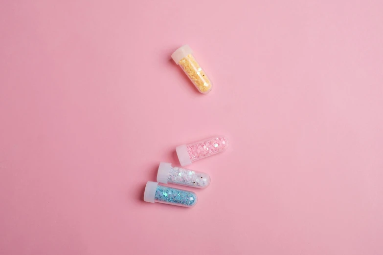 a couple of toothbrushes sitting on top of a pink surface, inspired by Pearl Frush, pexels, visual art, glitter crystals, 4 colors, pills, glitter gif