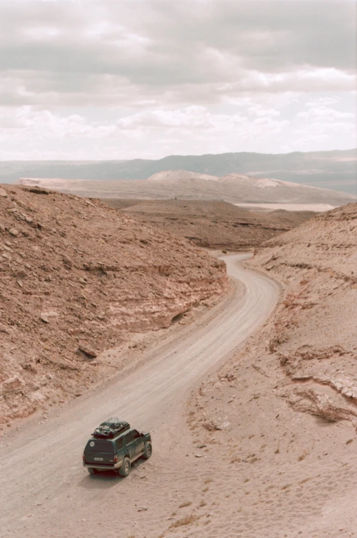 a car driving down a dirt road in the desert, les nabis, looking down from above, eytan zana, color photo, vast expansive landscape