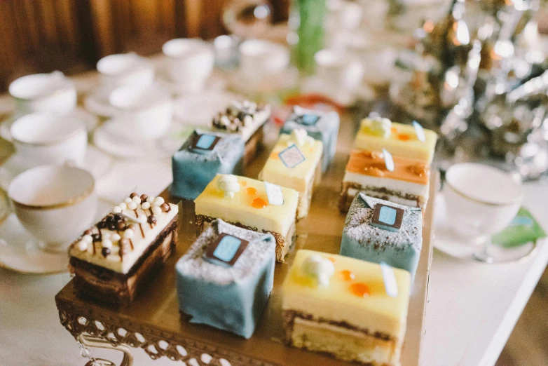 a table topped with lots of different types of cakes, a tilt shift photo, by Emma Andijewska, unsplash, art nouveau, square, blue, rectangle, tea