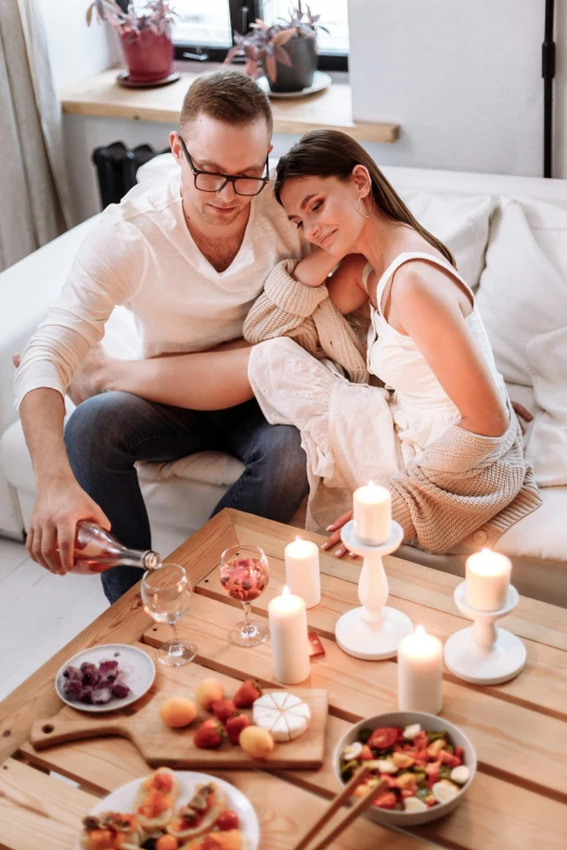 a man and woman sitting on a couch in a living room, pexels contest winner, romanticism, white candles, picnic, wearing white pajamas, ekaterina