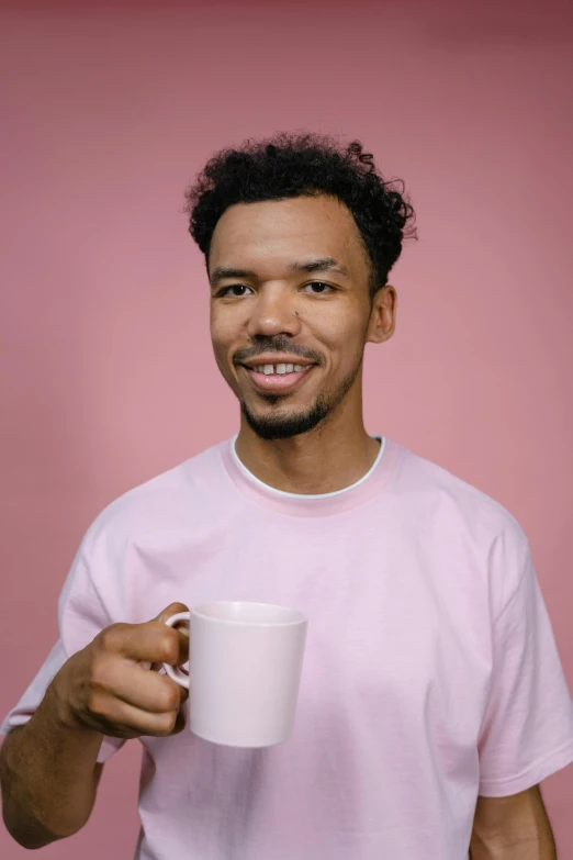 a man in a pink shirt holding a cup of coffee, nonbinary model, alexis franklin, mixed race, taken in the early 2020s