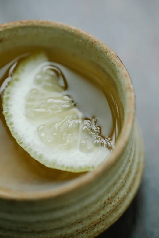 a bowl of liquid with a slice of lemon in it, inspired by Kanō Shōsenin, intricate detail, skewed shot, promo image, clay