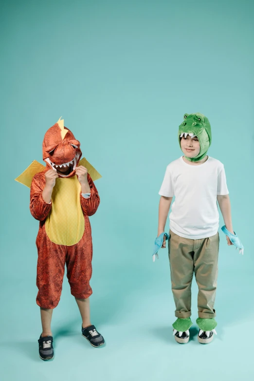 two boys in dinosaur costumes standing next to each other, inspired by Adam Rex, pexels, surrealism, dentist, charmander, plain background, wearing gloves