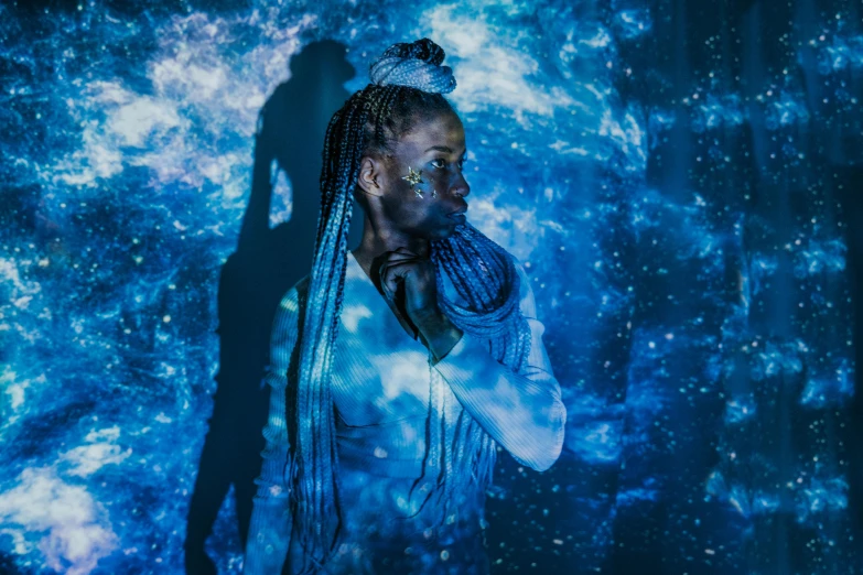 a woman with dreadlocks standing in front of a blue background, pexels contest winner, afrofuturism, holographic projection, alone in a nebula, dramatic white and blue lighting, calarts