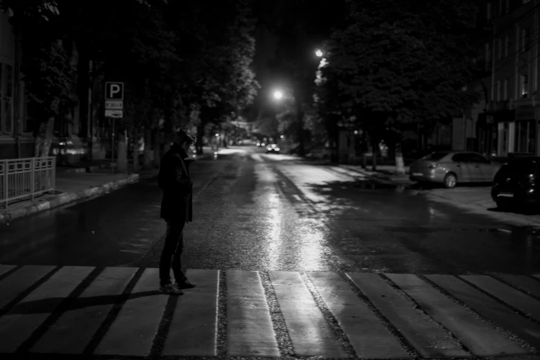 a person standing in the middle of a street at night, a black and white photo, by Giuseppe Avanzi, pexels contest winner, realism, after rain and no girls, sad cop looking at a, konstantin porubov, musician