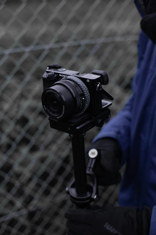 a close up of a person holding a camera on a tripod, walking towards the camera