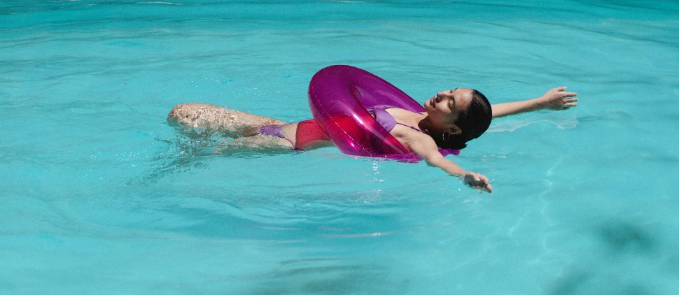 a woman floating in a pool with a life preserver, by Arabella Rankin, pexels contest winner, smooth fuschia skin, magenta, seasonal, transparent background