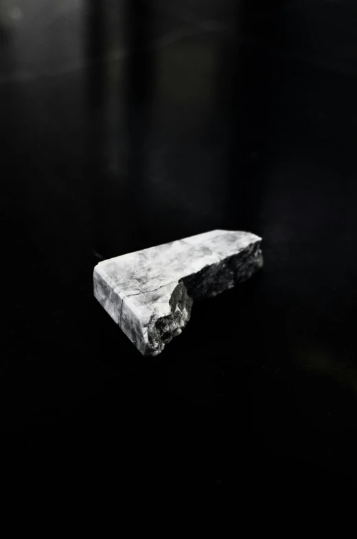 a rock floating on top of a body of water, an album cover, by Patrick Pietropoli, unsplash, conceptual art, coal dust, white on black, virgil abloh, made of stone