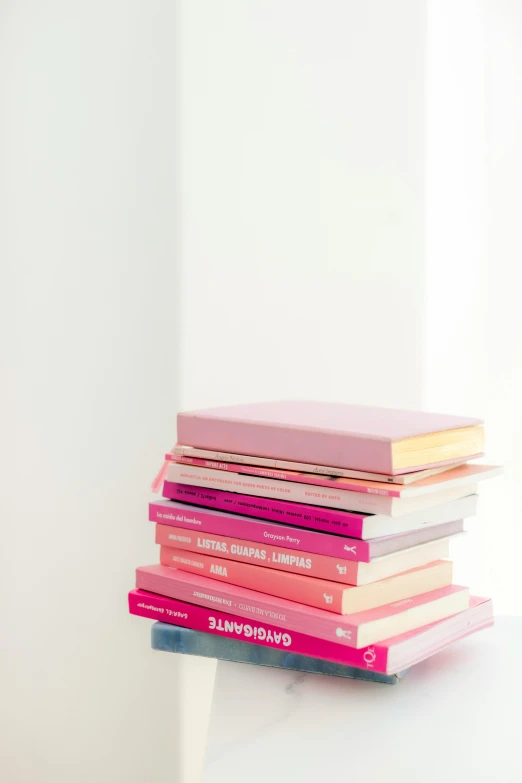 a stack of books sitting on top of a white table, petal pink gradient scheme, ((pink)), off - white collection, no watermark