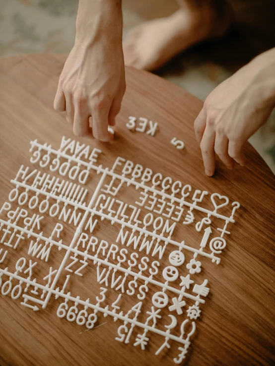 a person sitting on top of a wooden table, a jigsaw puzzle, inspired by Cerith Wyn Evans, unsplash, ascii art, puffy sticker, display font, game board, 8 k character details