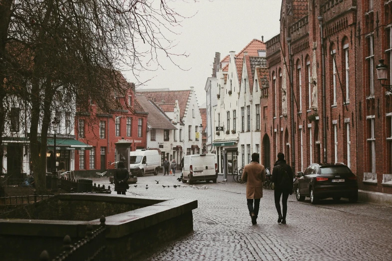 two people walking down a cobblestone street, by Jan Tengnagel, visual art, background image, brown, cosy vibes, college