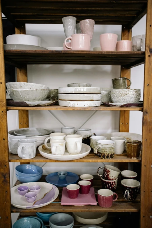 a wooden shelf filled with dishes and cups, in a workshop, ecommerce photograph, looking towards camera, cream