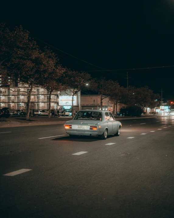 a car driving down a street at night, in the middle of the street