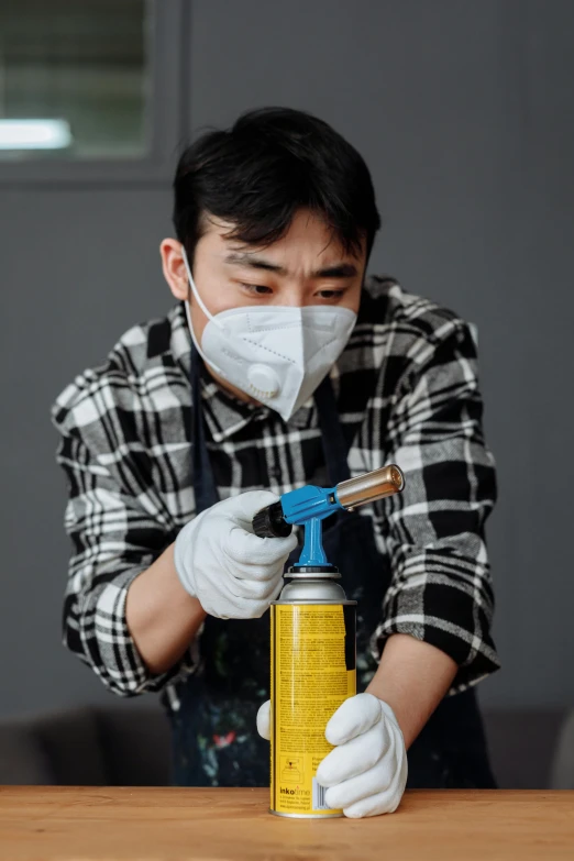 a man wearing a mask and gloves sprays down a wooden table, an airbrush painting, by Jang Seung-eop, pexels contest winner, sharing an oxygen tank, 64x64, mechanic, asian male