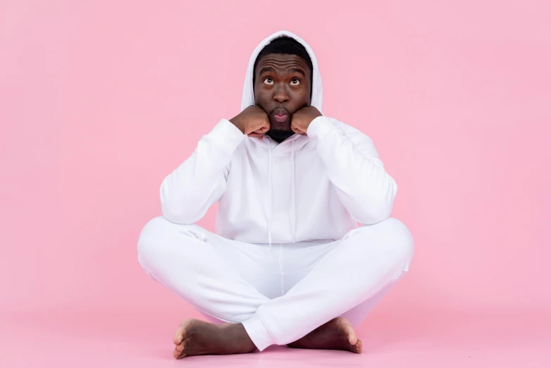 a man in a white hoodie sitting on the floor, trending on pexels, happening, pink clothes, mkbhd, funny and silly, solid background