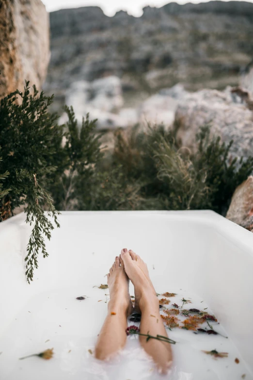 a person laying in a bathtub with their feet in the water, a picture, inspired by Elsa Bleda, trending on pexels, renaissance, on a cliff, eucalyptus, bubbly, rugged