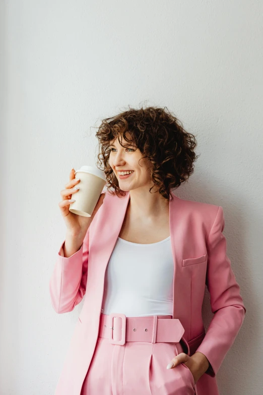 a woman in a pink suit holding a cup of coffee, trending on pexels, renaissance, curly brown hair, aussie baristas, professional profile picture, samma van klaarbergen