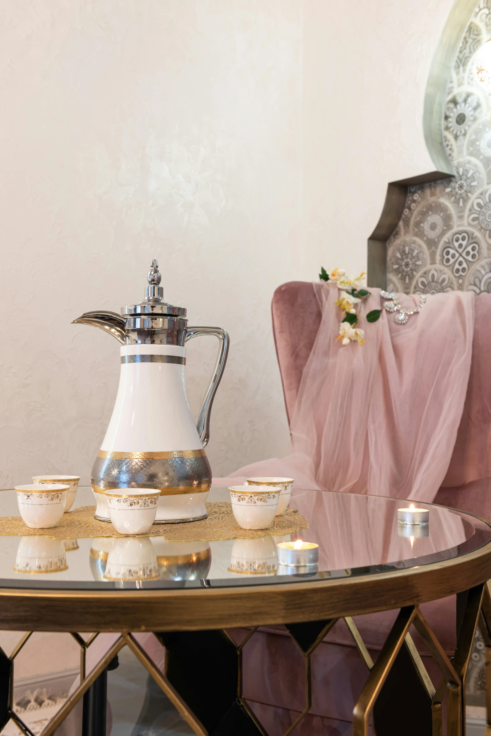 a coffee pot sitting on top of a table next to a chair, inspired by Riad Beyrouti, art nouveau, spa, romantic style, afar, silver with gold trim