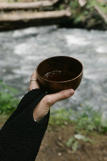 a person holding a bowl in front of a river, walnut wood, dark brown, kanamemo, item