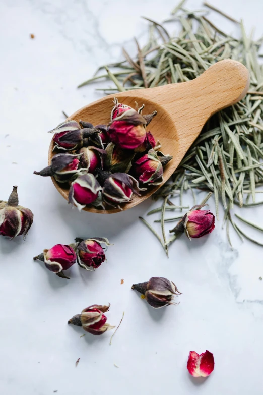 a wooden spoon filled with dried rose buds, inspired by Ruth Jên, ingredients on the table, herb, wine, tea