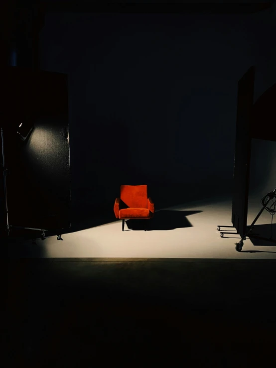 a red chair sitting on top of a white floor, inspired by Arnold Newman, unsplash contest winner, video art, dramatic lowkey studio lighting, ( ( theatrical ) ), behind the scenes, light source from the left