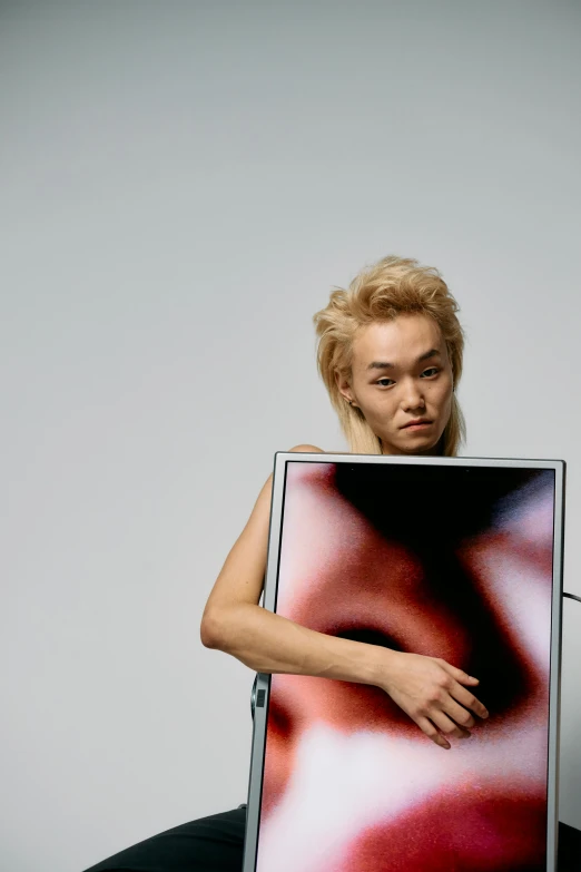 a woman sitting in front of a laptop computer, an album cover, inspired by Gao Cen, unsplash, hugh kretschmer, futuristic tetsuo, woman holding sign, a blond