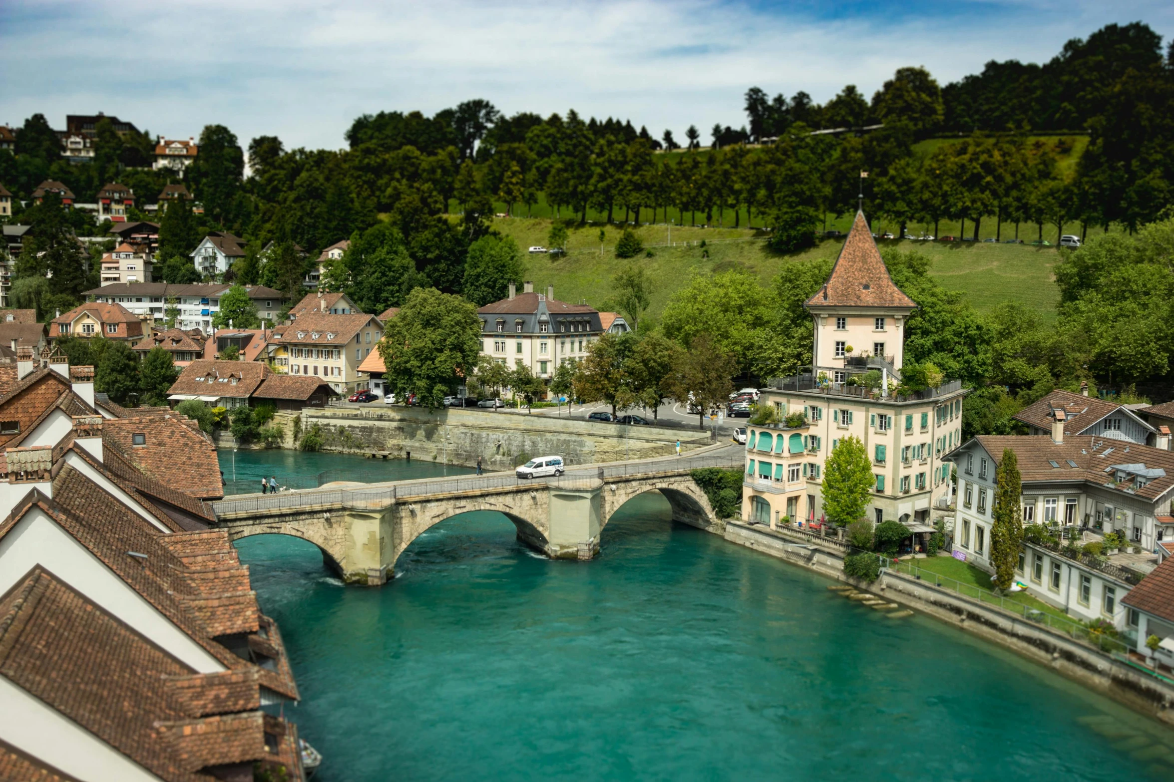 a river running through a town next to a bridge, inspired by Karl Stauffer-Bern, pexels contest winner, renaissance, square, blue and green water, dezeen, brown