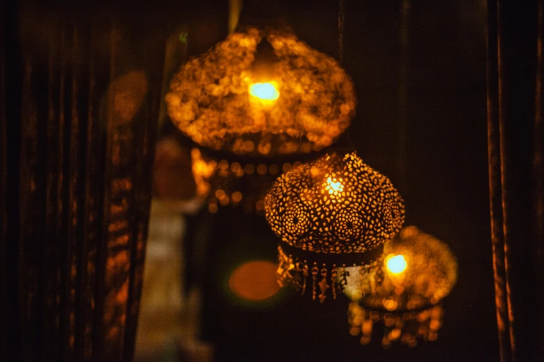 a bunch of lights hanging from a ceiling, inspired by Elsa Bleda, pexels, arabesque, warm lantern lighting, gold filigree, candlelight, dimly - lit