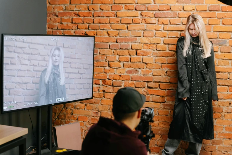 a woman standing next to a man in front of a tv, a picture, trending on pexels, at a fashion shoot, ukraine. professional photo, photo taken with canon 5d, high detailed photography cape