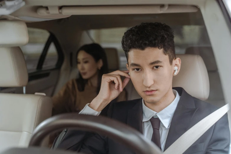 a man sitting in a car talking on a cell phone, by Julia Pishtar, trending on pexels, renaissance, earbuds jewelry, wearing a blazer, cai xukun, caring fatherly wide forehead