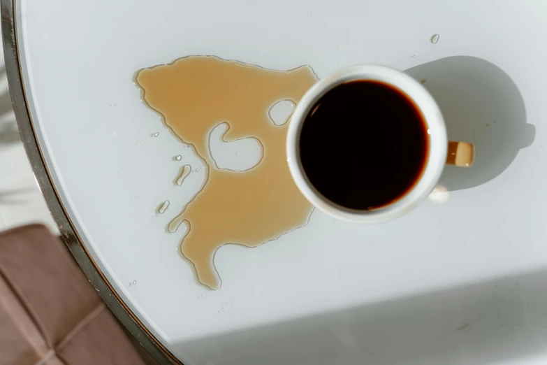 a cup of coffee sitting on top of a table, leaking oil, extremely graphic, served on a plate, head down