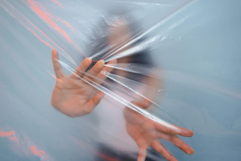 a blurry image of a person holding an umbrella, an album cover, inspired by Anna Füssli, unsplash, plasticien, plastic wrap, emerging hands, lines and movement, suspended in zero gravity
