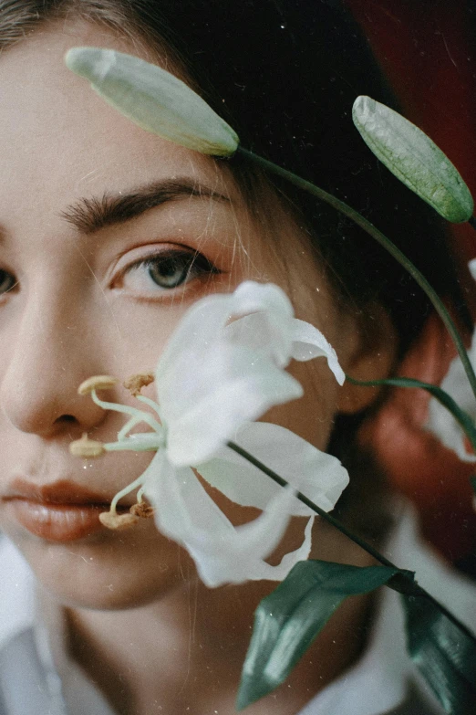 a woman holding a flower in front of her face, inspired by Elsa Bleda, trending on pexels, hyperrealism, white lilies, portrait sophie mudd, woman made of plants, medium close up portrait