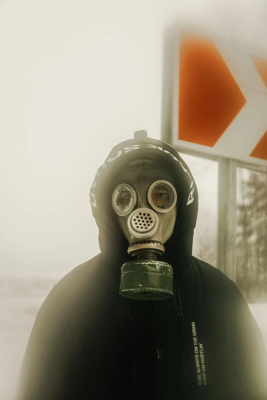 a man wearing a gas mask standing in front of a street sign, pexels contest winner, cold environment, hostages, toxic, low quality photo