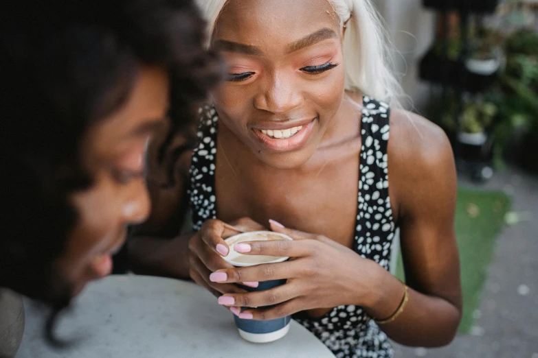 two women sitting at a table with a cup of coffee, trending on pexels, black teenage girl, blushing, closeup photograph, 15081959 21121991 01012000 4k