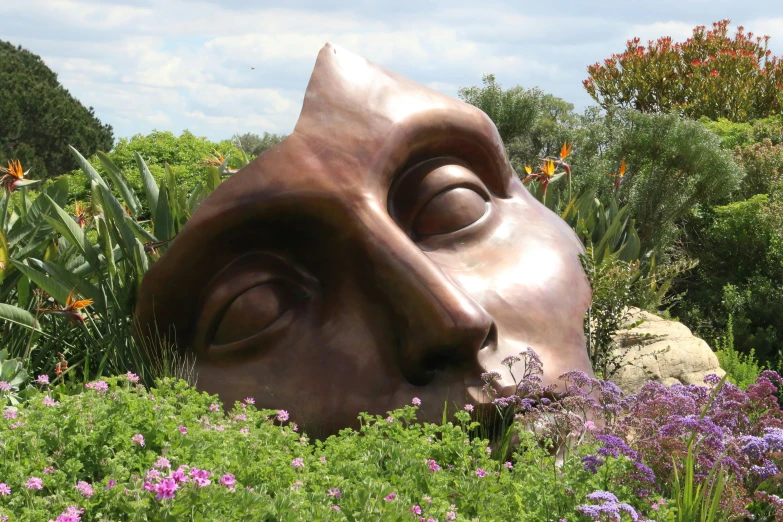 a close up of a sculpture in a field of flowers, inspired by Dali, bronze face, pixar studios, asleep, vista view