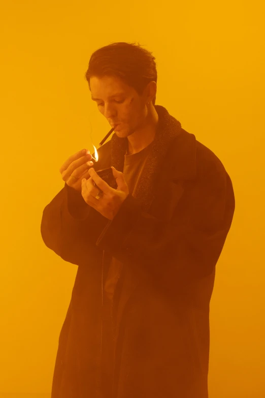 a man in a black coat smoking a cigarette, an album cover, unsplash, bauhaus, yellow tint, chandler bing, travis scott, orange light