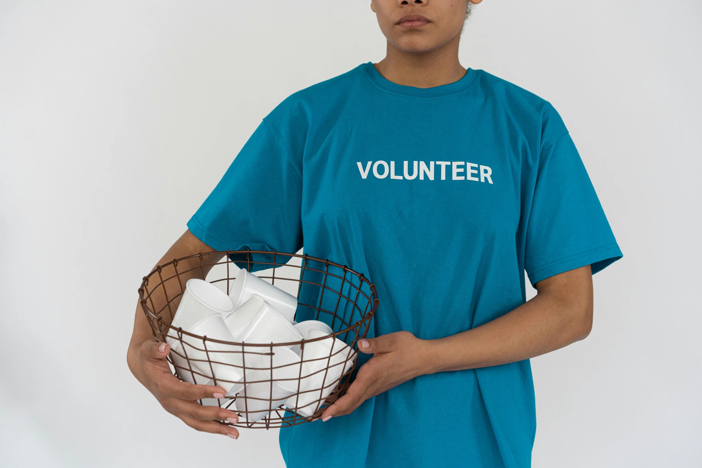 a man in a blue shirt holding a basket of towels, by Helen Stevenson, pexels contest winner, arte povera, tshirt, teal uniform, woman holding sign, on white background