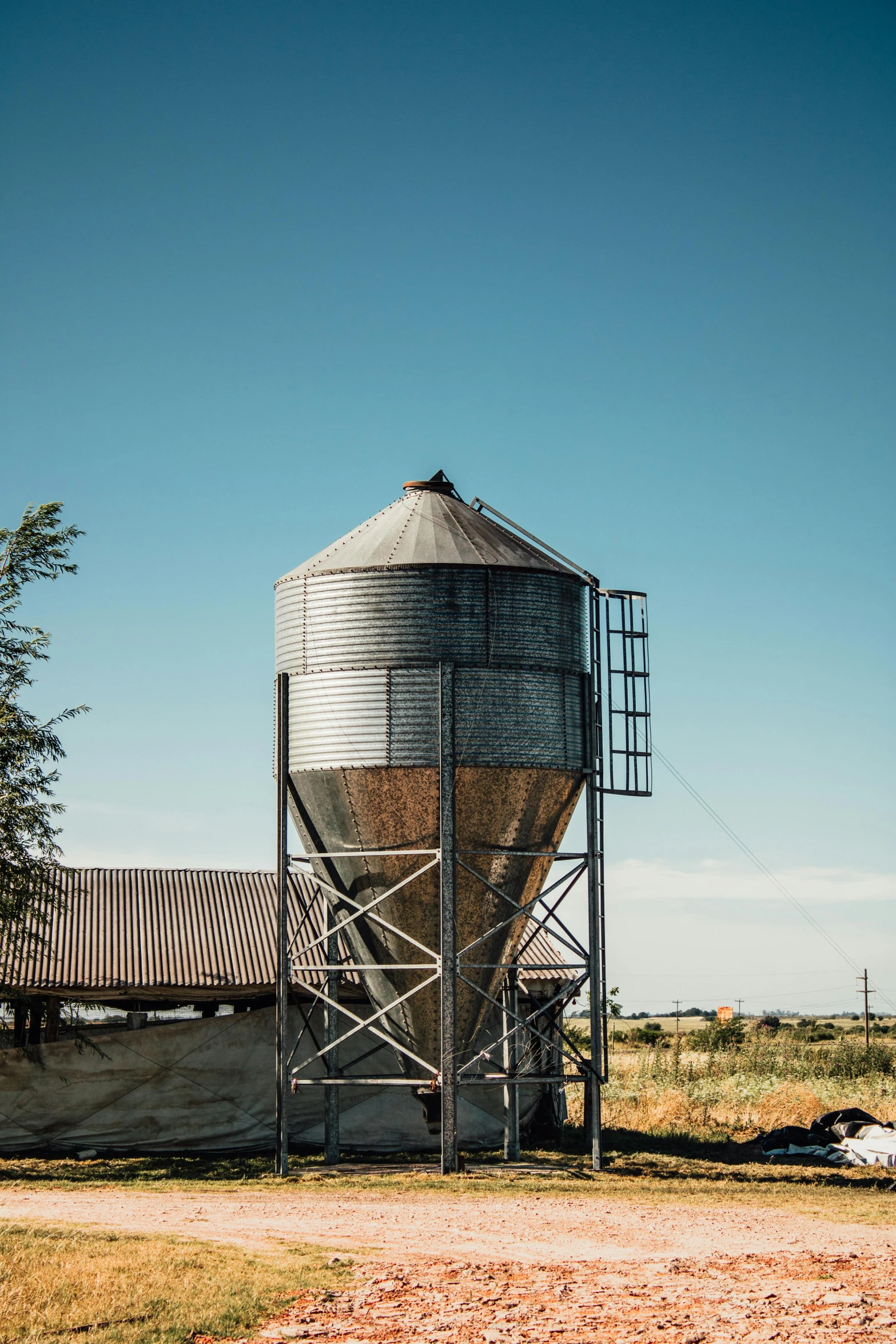 a large metal silo sitting in the middle of a field, a picture, unsplash, old west, cone shaped, outside in a farm, full daylight