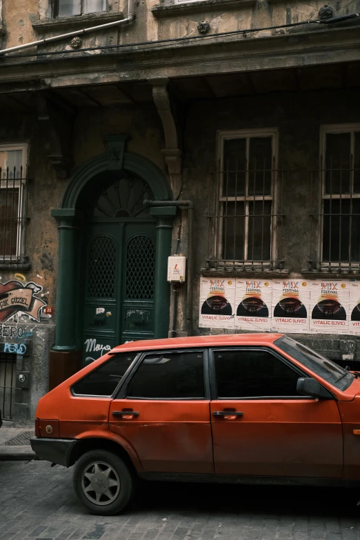 a red car parked in front of a building, a photo, inspired by Elsa Bleda, pexels contest winner, graffiti, turkey, old library, gray and orange colours, vhs footage of a movie set