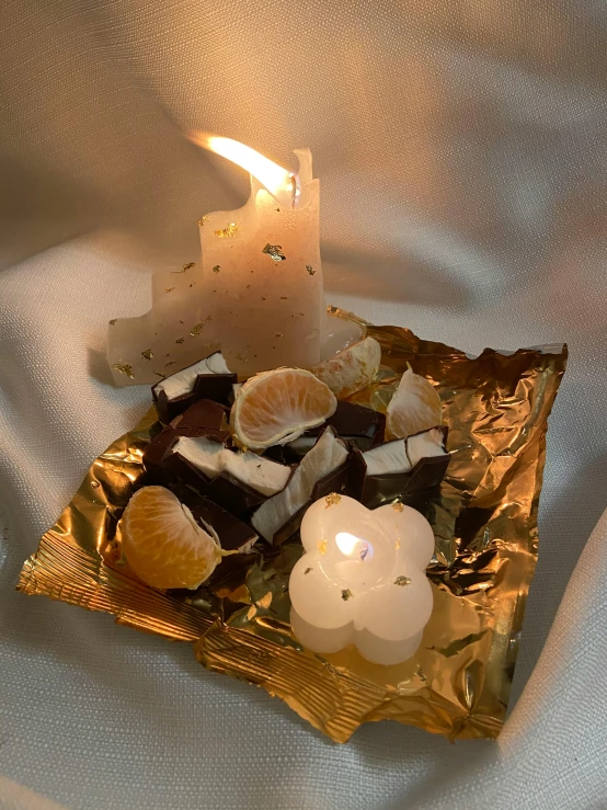 a lit candle sitting on top of a piece of foil, by Henriette Grindat, chocolate, holy themed, citrinitas, soft white glow