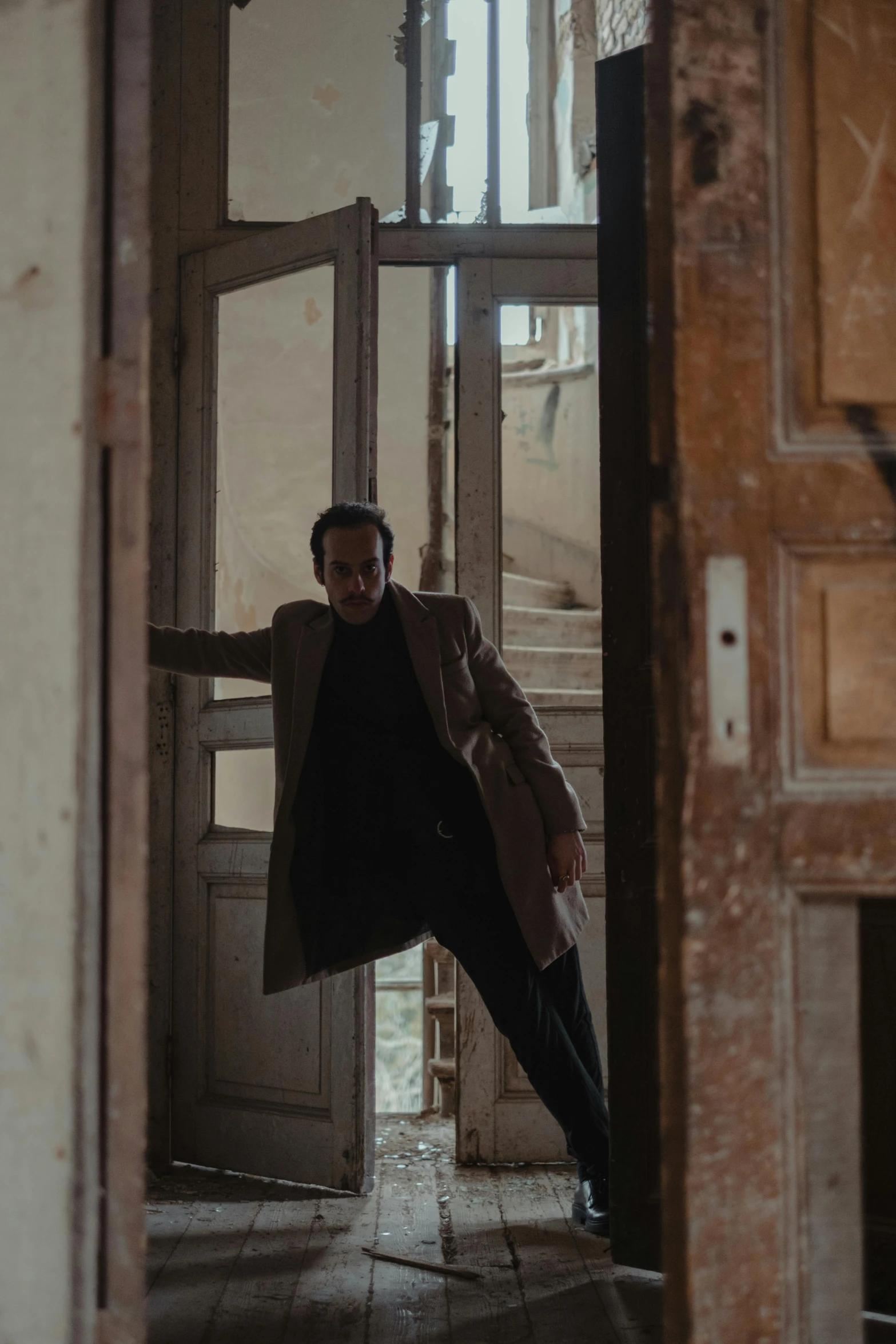 a man that is standing in a doorway, an album cover, by Carlo Martini, pexels contest winner, movie action still frame, [ theatrical ], chasing action scene, old apartment