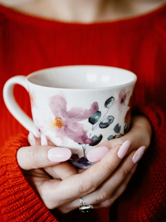 a woman holding a coffee cup in her hands, a watercolor painting, trending on pexels, celestial red flowers vibe, unclipped fingernails, tea cup, profile image